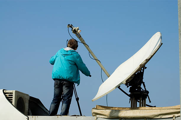 Técnico con medidor de campo orientando una antena parabólica en azotea