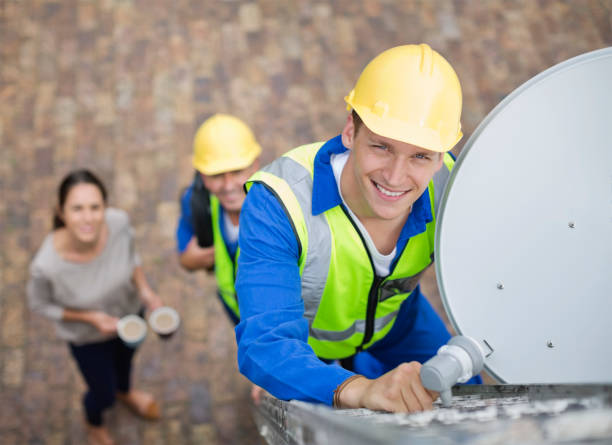 Técnico orientando una antena parabólica en una azotea